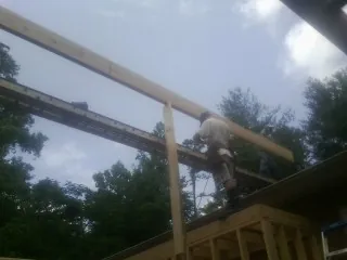 Carpenter setting a ridge beam over a new addition frame — Ice Dam Removal by Roofing Brothers in Purlear