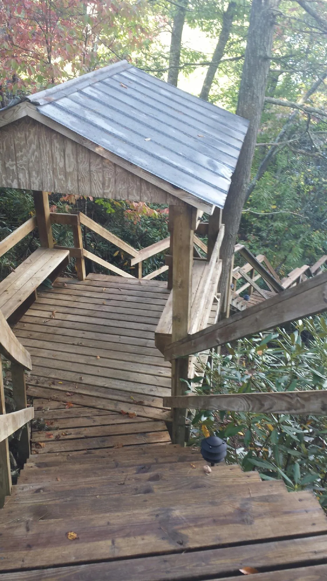 Metal roofed shelter over wooden steps on a wooded walkway — Skylight Repair & Installation work by our crew in Purlear